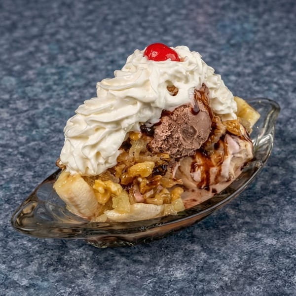 A banana split with chocolate and vanilla ice cream, whipped cream, nuts, and a cherry.
