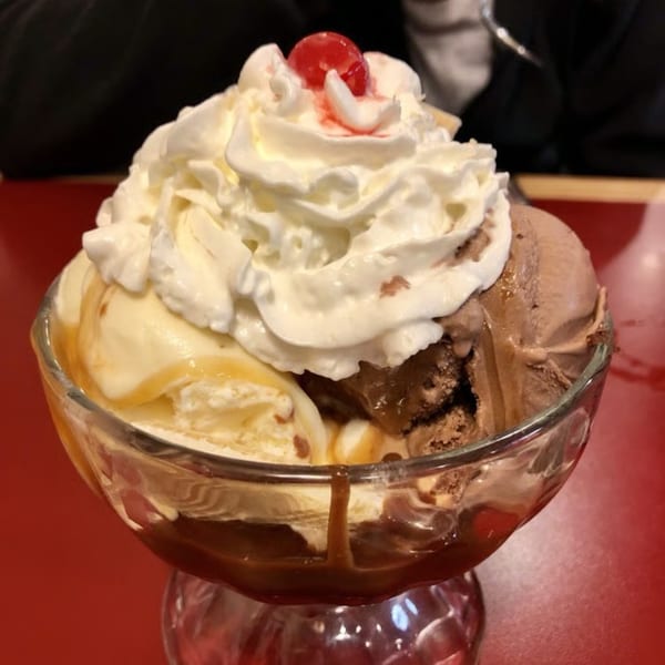 A Mayberry Ice Cream sundae with vanilla and chocolate ice cream, whipped cream, and a cherry.