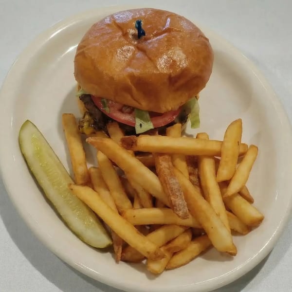 A Mayberry Ice Cream Restaurants burger with fries and a pickle spear on a white plate.